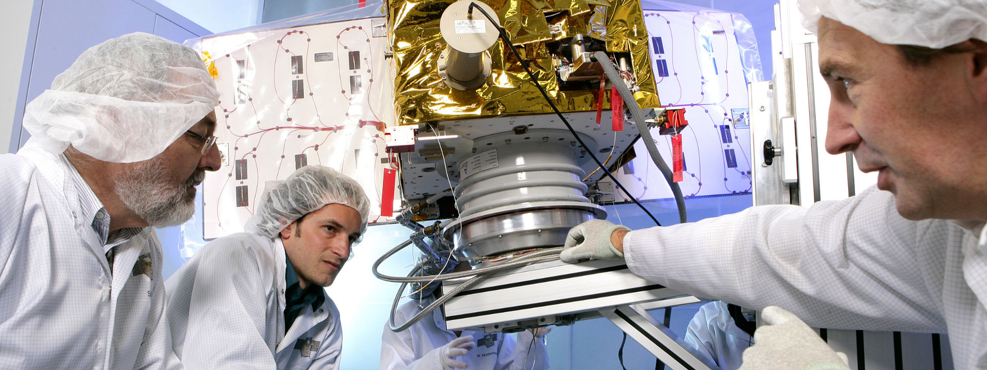 Two OHB employees working on satellites in a clean room